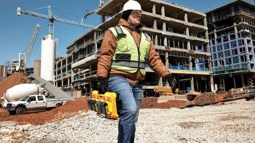 A man carrying the 4-port Charger in front of a construction site.