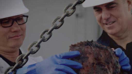 Two men wearing hard hats inspecting catch.